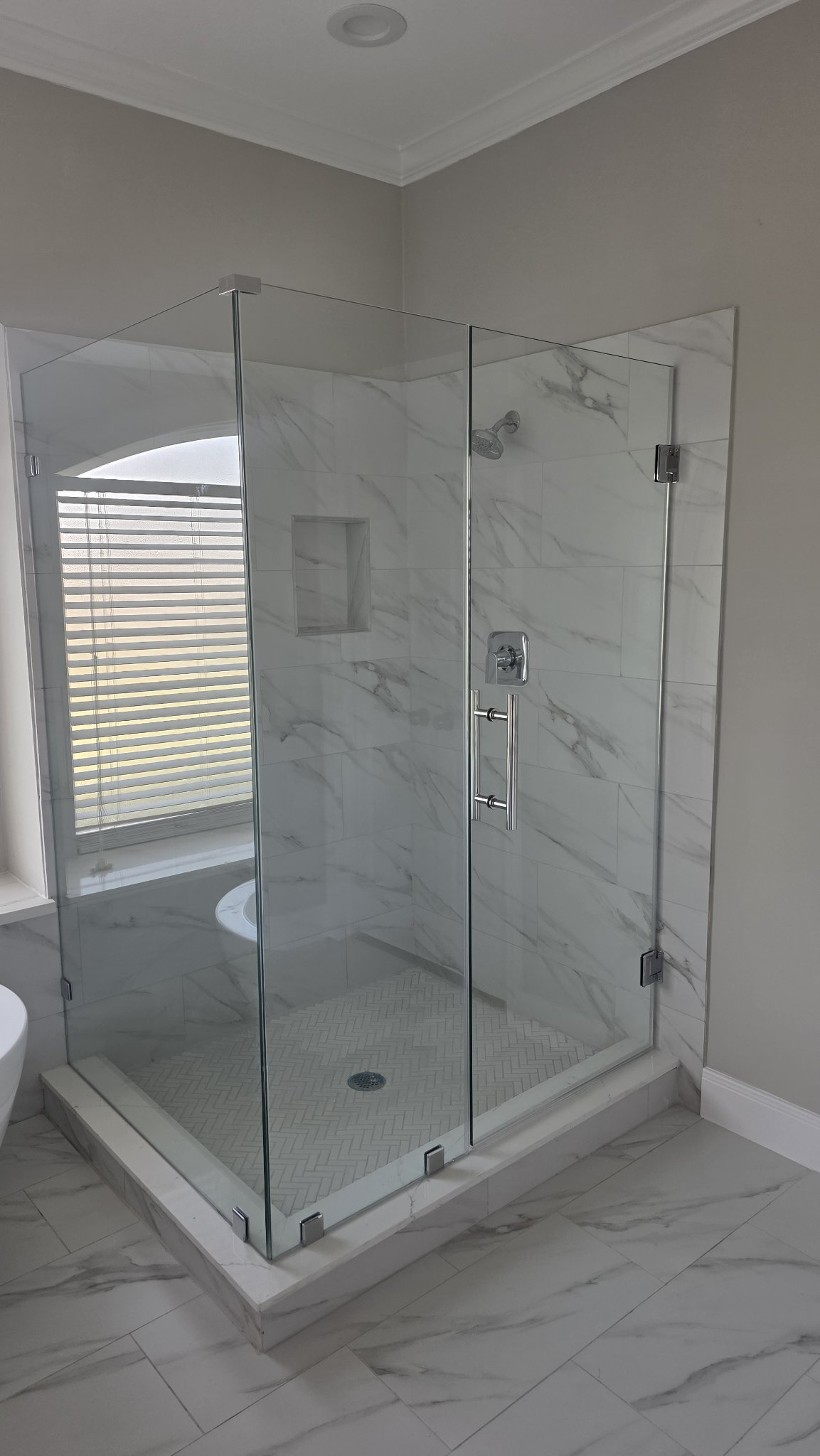 Foto de referencia del baño en ángulo 90° sin muro ni notch: shower de vidrio en esquina normal, con puerta de bisagras a la pared y panel de retorno