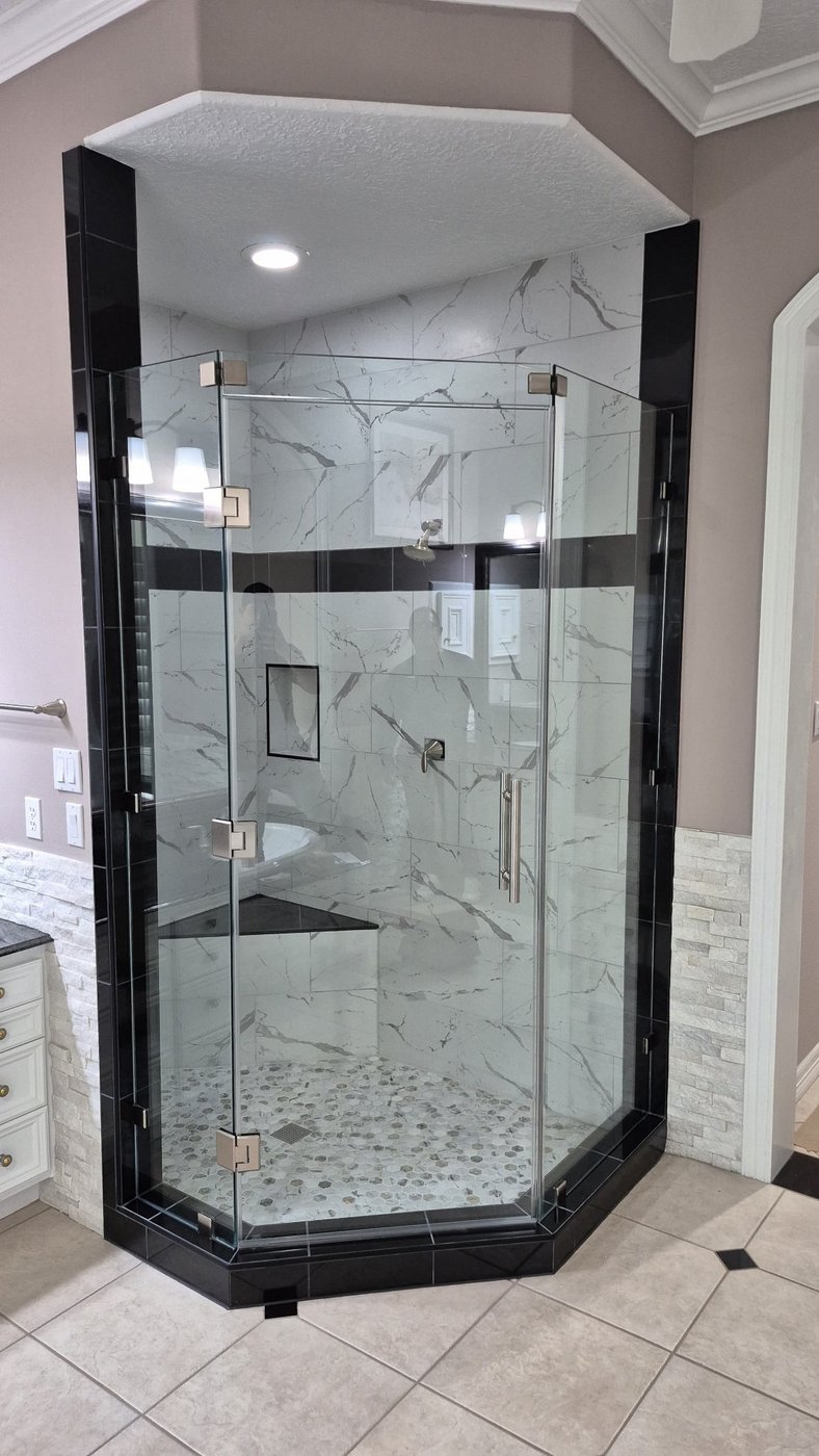 Trabajo de Glas Plus: ángulo 135° neo-angle con herraje de níquel cepillado en un shower de azulejo tipo mármol con franja negra