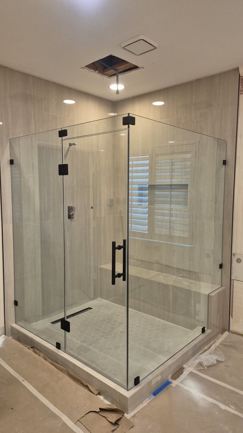 Trabajo de Glas Plus: ángulo 90° glass to glass con herraje negro y banca dentro del shower