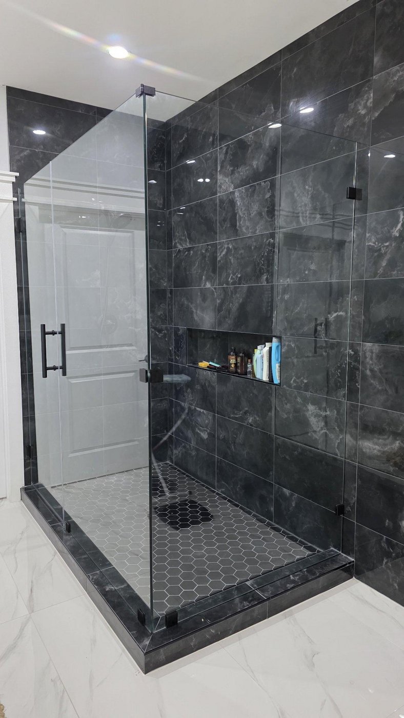 Trabajo de Glas Plus: ángulo 90° con herraje negro en un shower de mármol oscuro