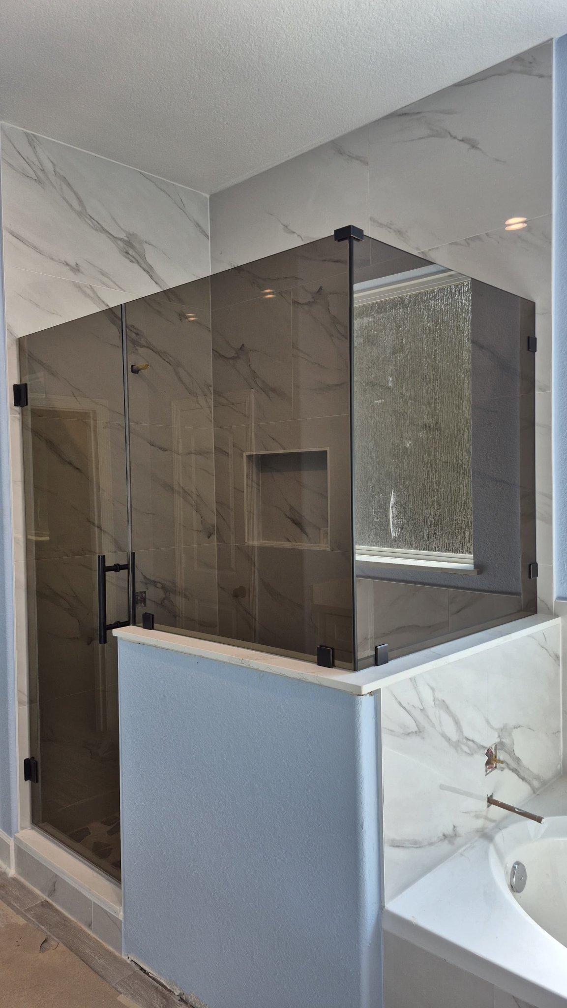 Trabajo de Glas Plus: shower en ángulo 90° con vidrio Bronze (tono bronce) sobre un muro, junto a la tina