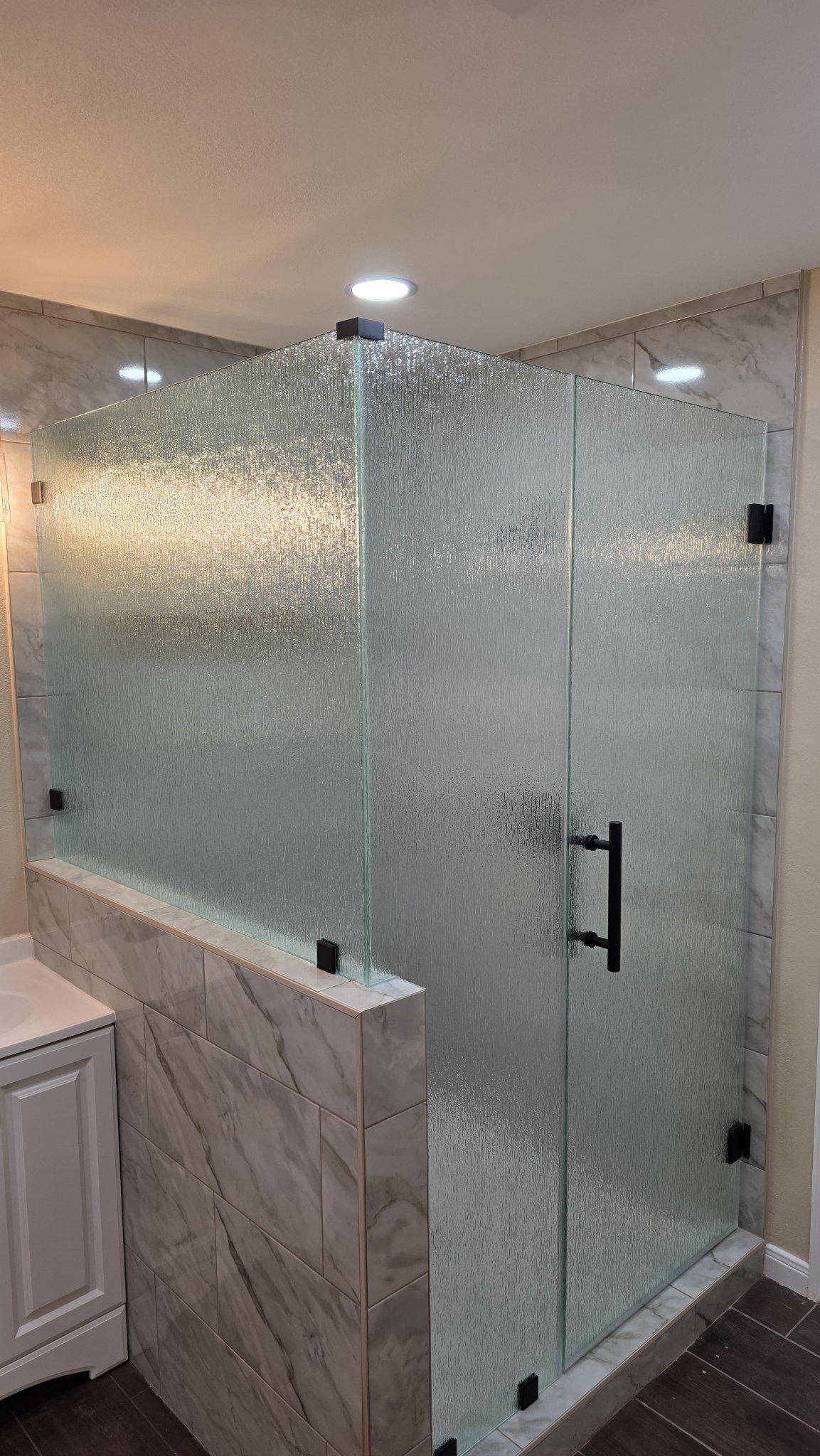 Trabajo de Glas Plus: shower en ángulo 90° con vidrio Rain (textura de lluvia) sobre un muro y herraje negro