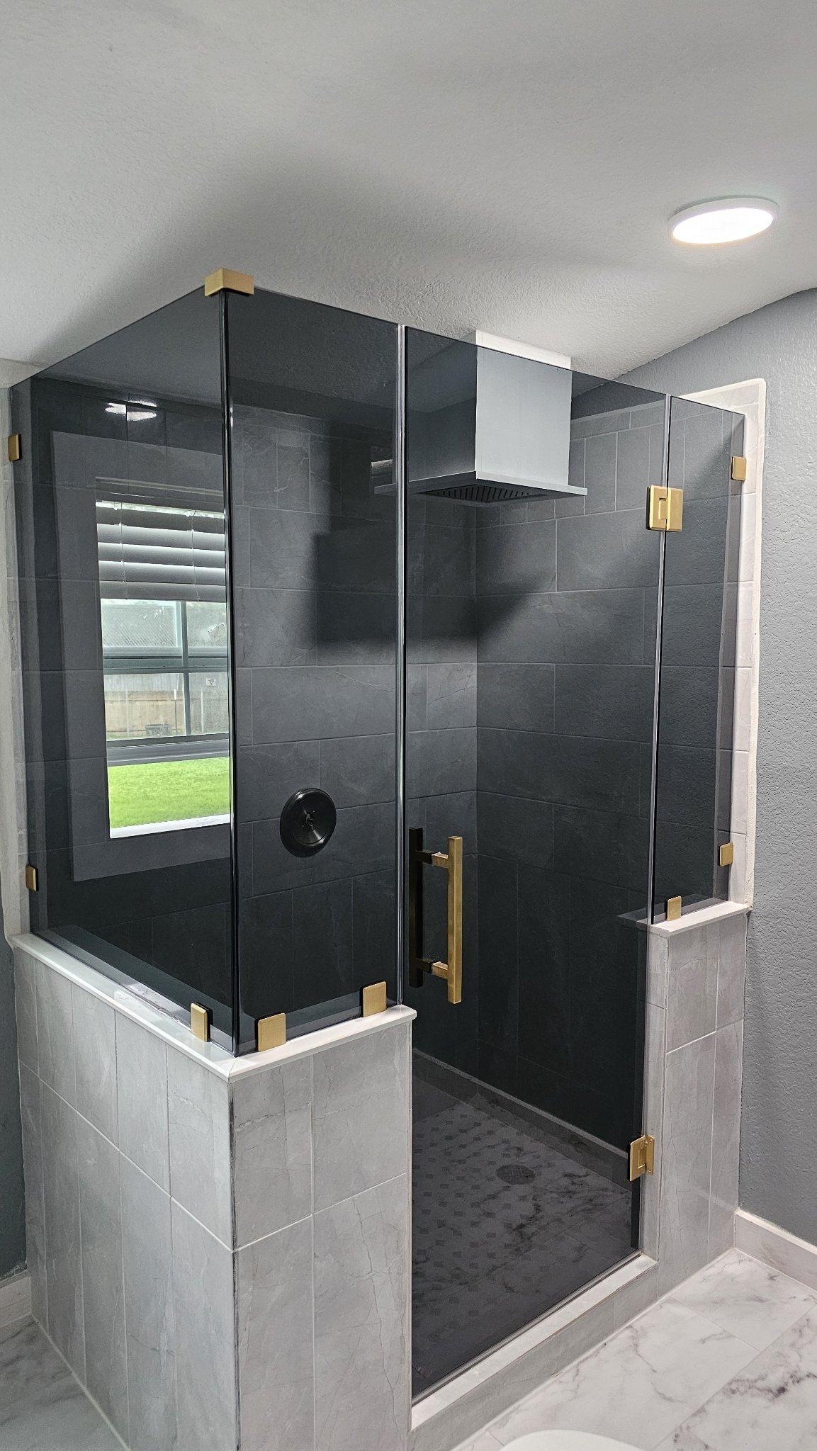 Trabajo de Glas Plus: shower en ángulo 90° con vidrio Grey (gris ahumado) montado sobre muros y herraje dorado