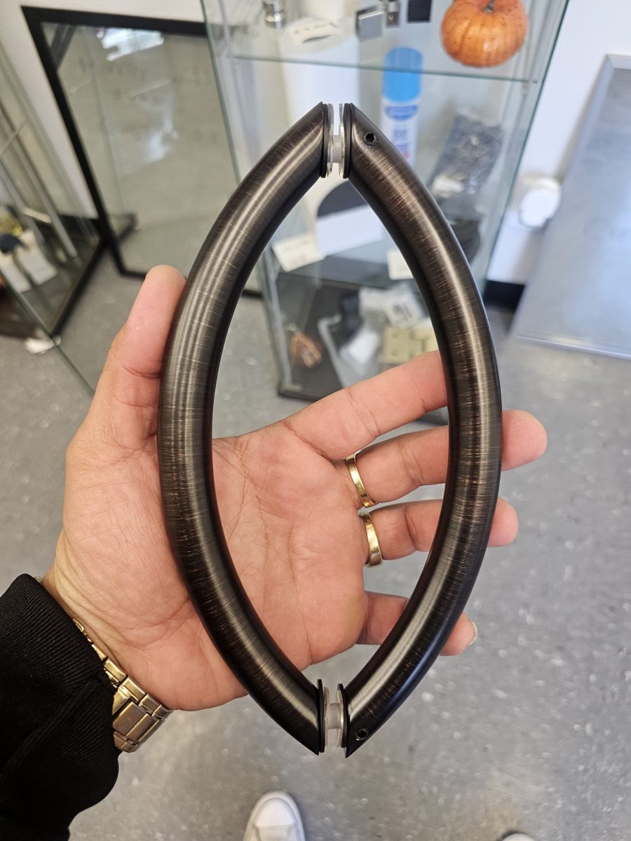 Manija ovalada en bronce oscuro cepillado de Glas Plus sostenida en una mano