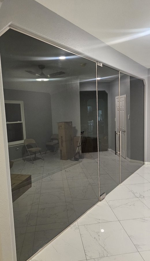 Ejemplo de órdenes especiales de Glas Plus: pared divisoria de vidrio ahumado sin marco con puerta, en el interior de una casa
