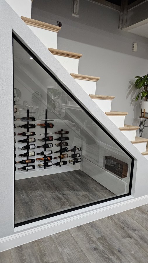 Ejemplo de órdenes especiales de Glas Plus: cava de vinos bajo la escalera cerrada con un panel de vidrio triangular con marco negro