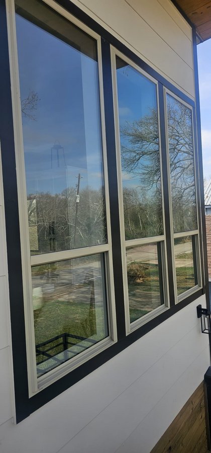 Ejemplo de ventanas de Glas Plus: tres ventanas altas con marco blanco y negro en el frente de una casa
