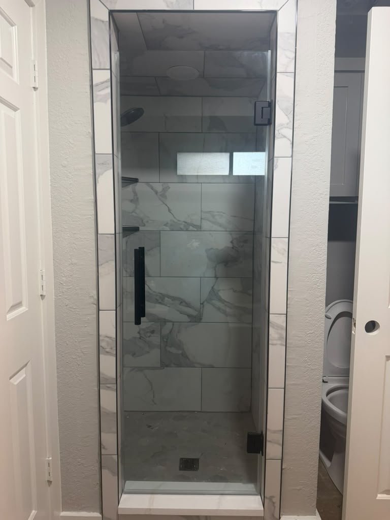 Single door con herraje negro instalada por Glas Plus en un shower de azulejo tipo mármol
