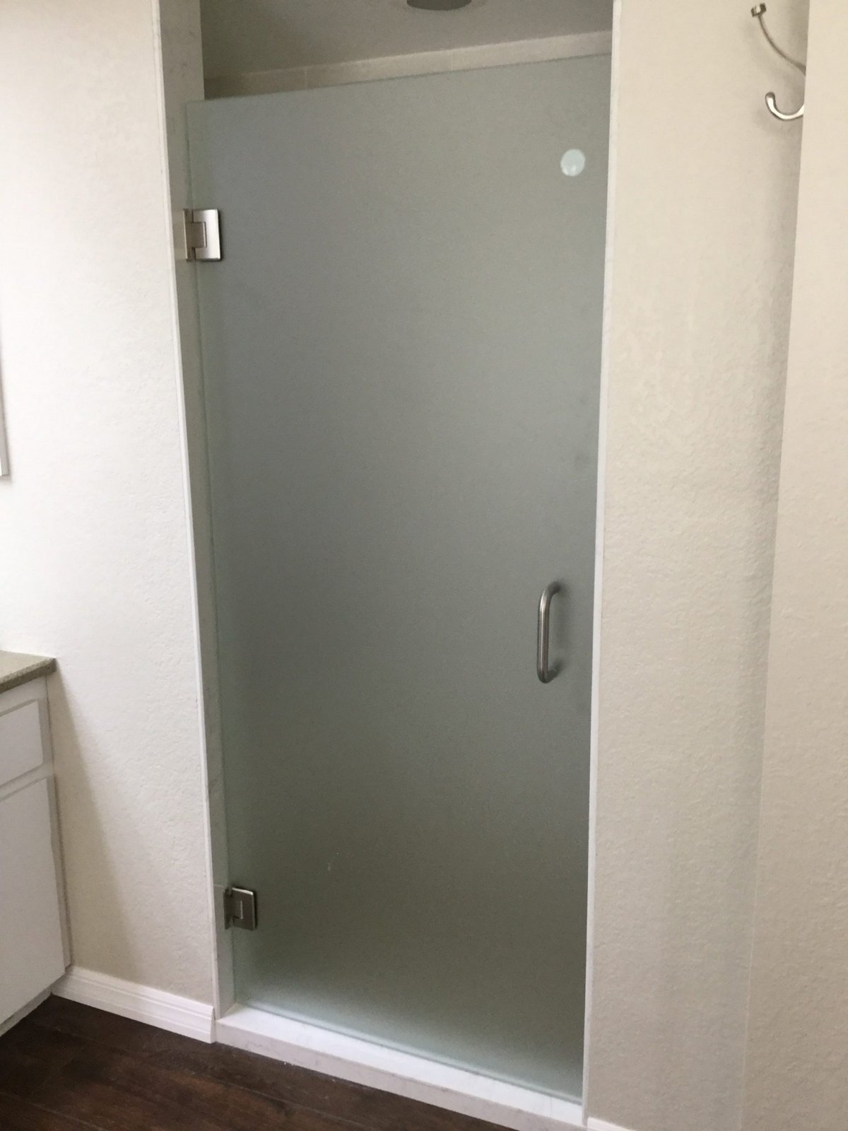 Single door con vidrio Frosted (opaco) y herraje brush nickel instalada por Glas Plus en un shower de paredes blancas