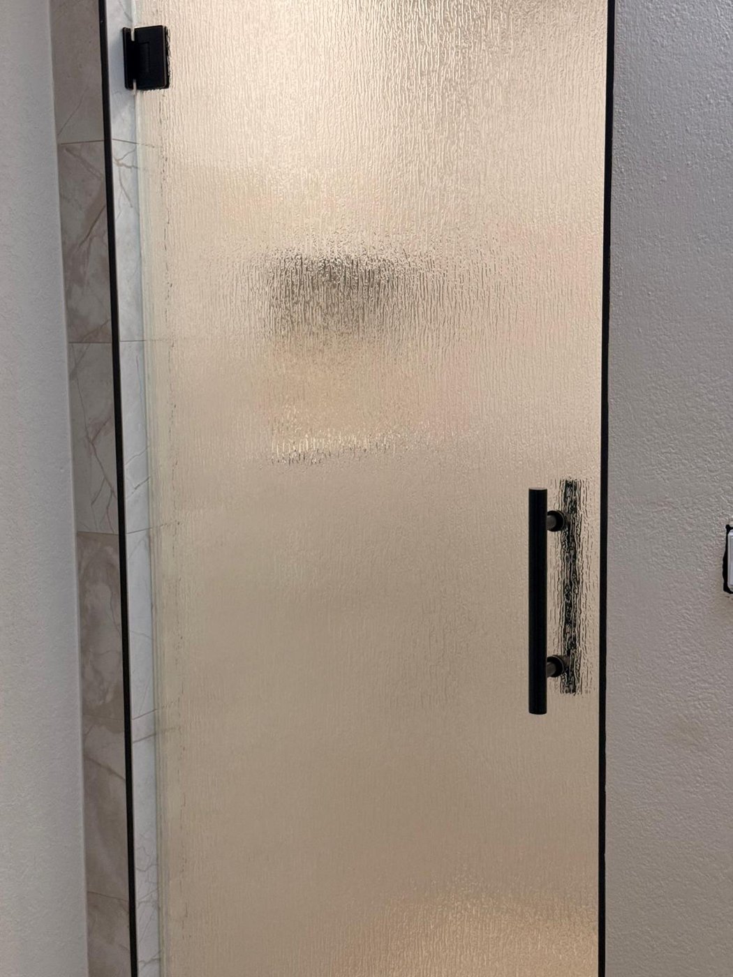 Single door con vidrio Rain (textura de lluvia) y manija negra instalada por Glas Plus