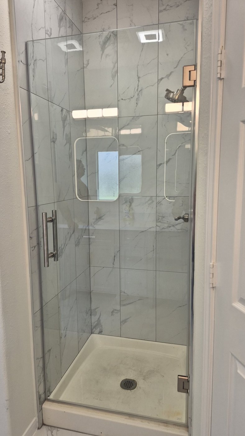 Single door con herraje brush nickel instalada por Glas Plus en un shower de mármol