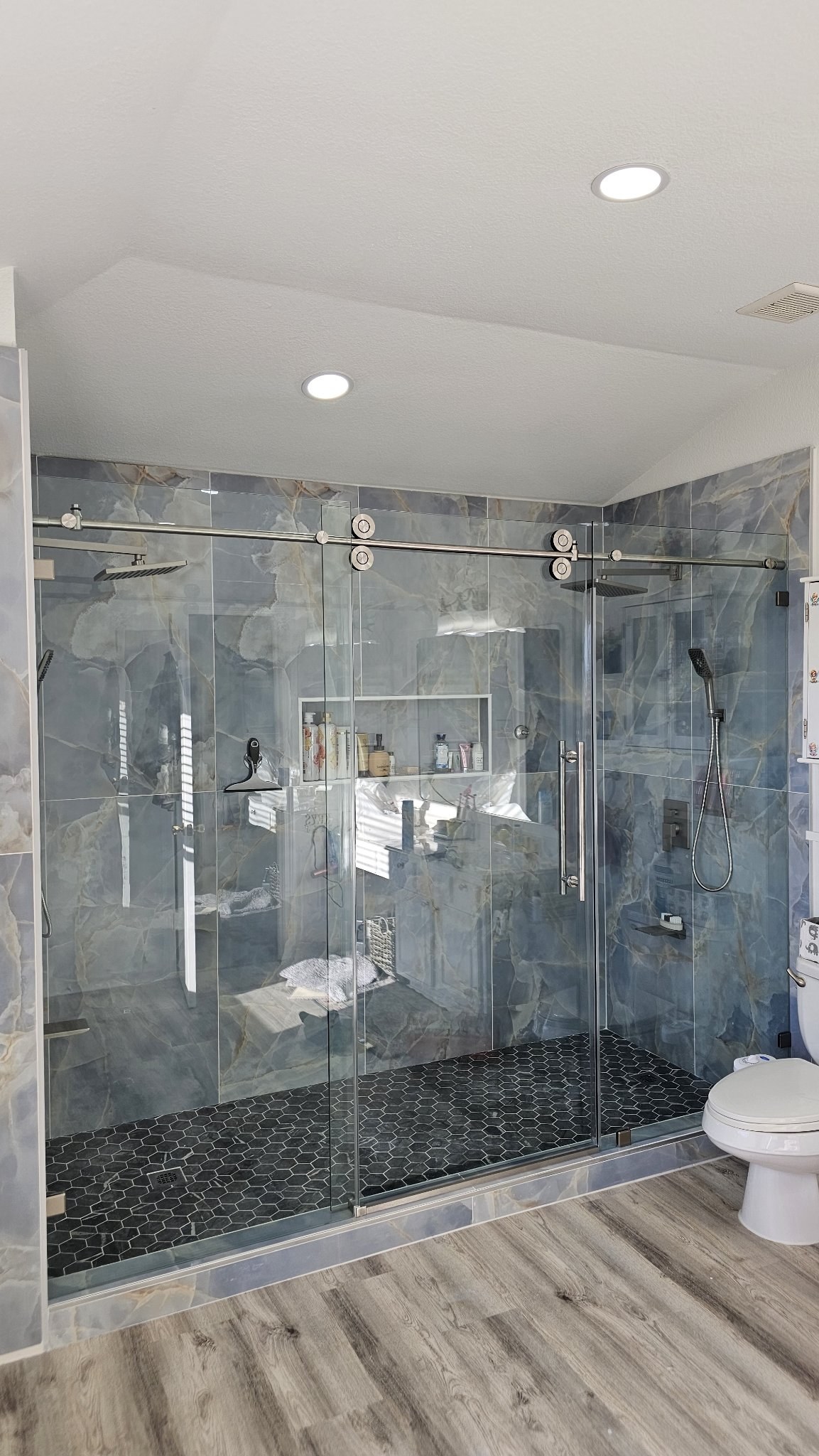 Sliding con puerta en el centro (panel fijo, puerta y panel fijo) con riel de brush nickel en shower de mármol azul con dos duchas