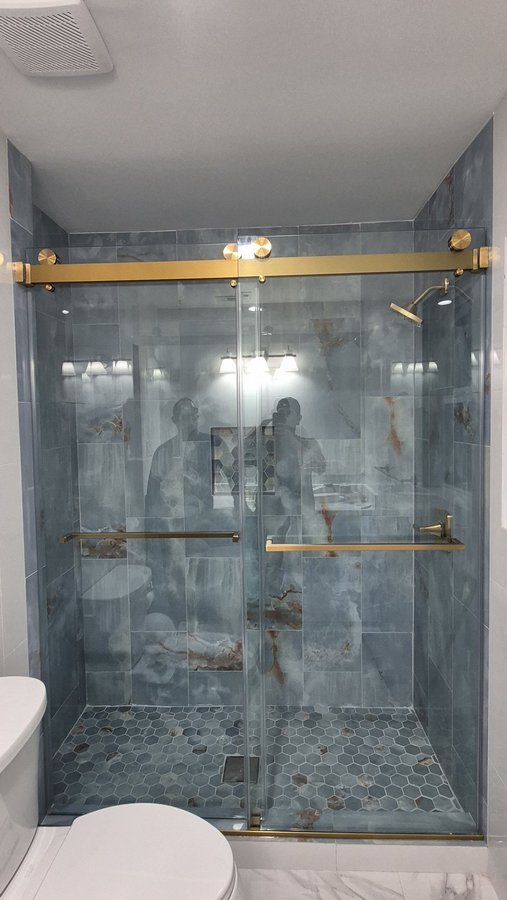 Sliding doble puerta con riel dorado en shower de azulejo blanco con nicho