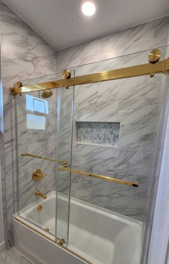 Sliding doble puerta con riel dorado sobre tina en baño de azulejo beige