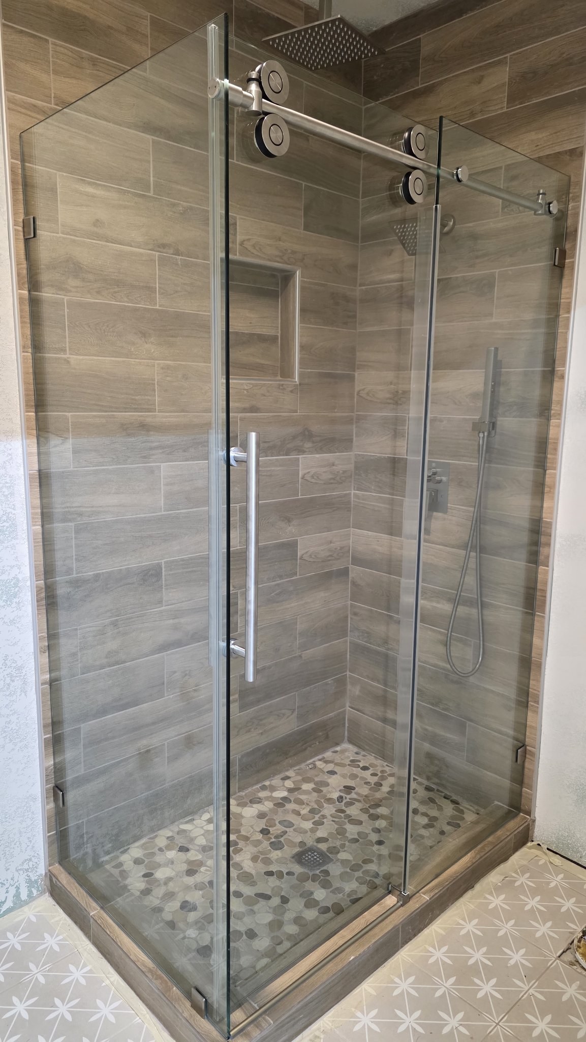 Sliding con retorno con riel de brush nickel en shower de azulejo tipo madera con nicho
