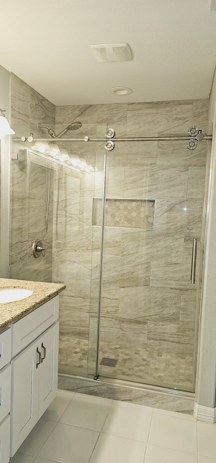 Sliding de una puerta con riel cromado y toallero en shower de azulejo mármol